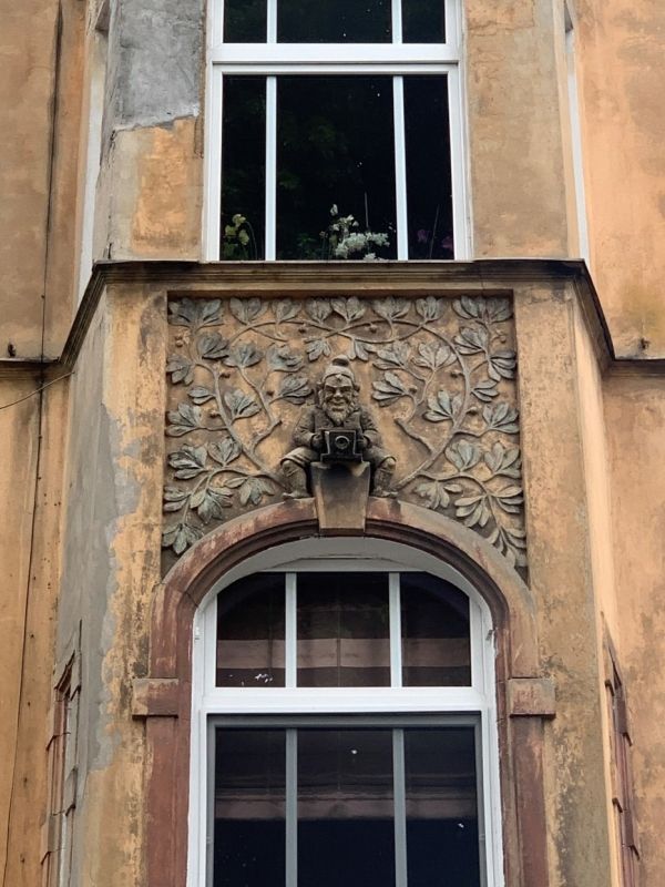 Two details of the facade of the tenement house: an owl and a dwarf with a camera