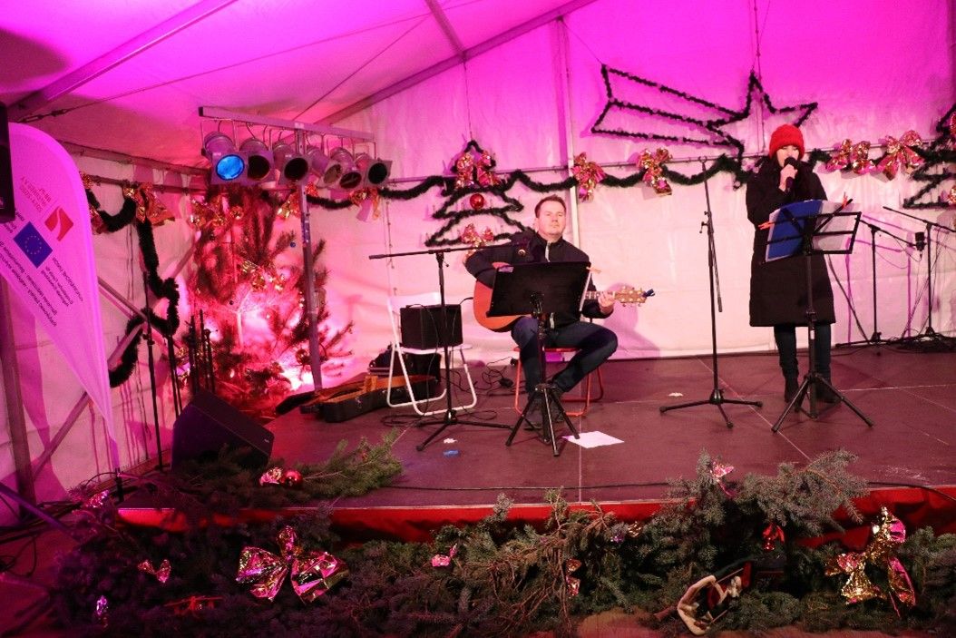 Bild: Gitarrenspieler und Sängerin auf einer weihnachtlichen Bühne